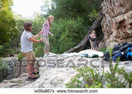 Stock Photo - Young group of people setting up tent on rocks. Fotosearch
