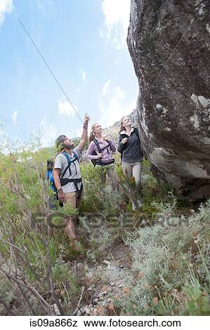 Young hikers looking up at large boulder View Large Photo Image Stock Photo - Young hikers looking up at large boulder. Fotosearch