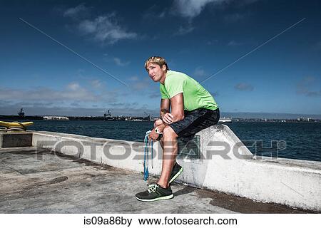 Stock Photo - Young man in sportswear resting on pier. Fotosearch