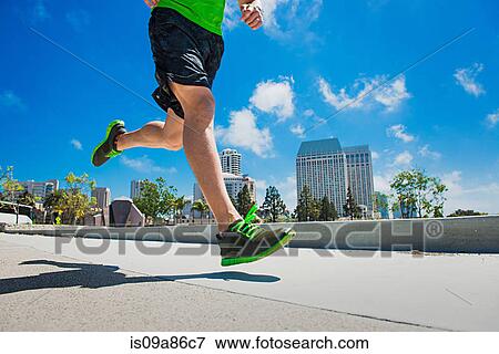 Stock Photo - Young man jogging in city, low section. Fotosearch