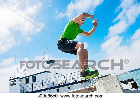 Stock Image - Young man jumping while fitness training. Fotosearch