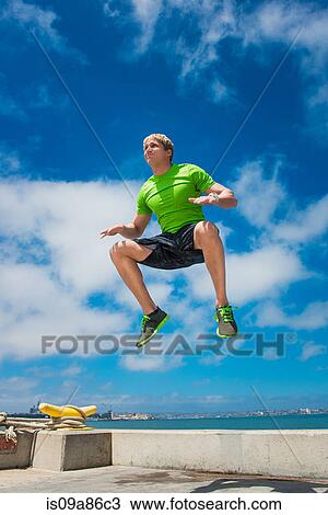 Stock Image - Young man jumping while fitness training. Fotosearch
