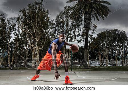 Young man playing basketball on court, portrait View Large Photo Image Picture - Young man playing basketball on court, portrait. Fotosearch