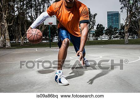 Young man playing basketball on court, close up View Large Photo Image Stock Photography - Young man playing basketball on court, close up. Fotosearch