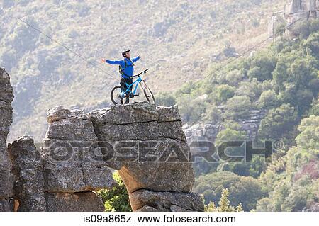 Young man with mountain bike and arms outstretched on rock View Large Photo Image Stock Photo - Young man with mountain bike and arms outstretched on rock. Fotosearch