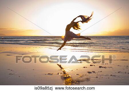 Young woman dancing on sunlit beach View Large Photo Image Stock Image - Young woman dancing on sunlit beach. Fotosearch
