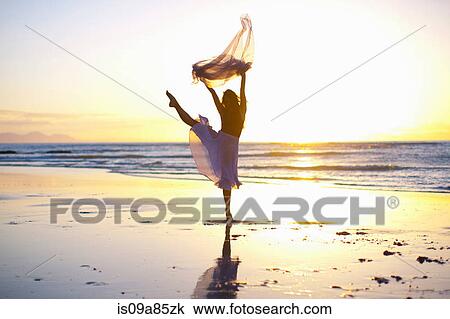 Young woman dancing on sunlit beach View Large Photo Image Stock Image - Young woman dancing on sunlit beach. Fotosearch