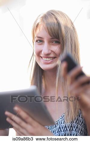 Stock Image - Young woman holding digital tablet. Fotosearch