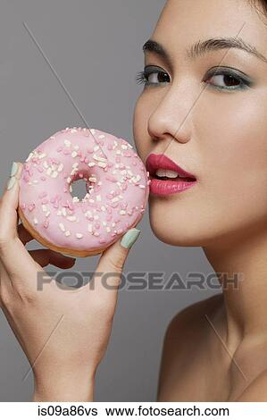 Young woman holding doughnut View Large Photo Image Stock Photograph - Young woman holding doughnut. Fotosearch