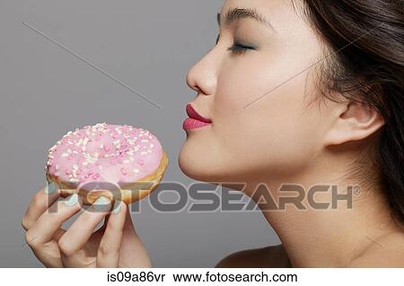 Stock Photography - Young woman holding doughnut. Fotosearch