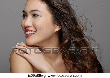 Stock Image - Young woman smiling in studio. Fotosearch