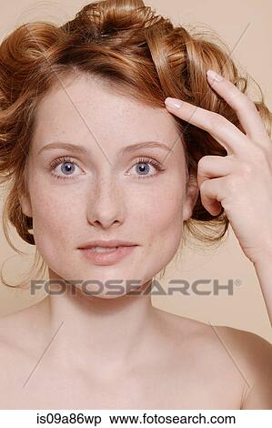 Stock Photography - Young woman with curly red hair biting lip. Fotosearch