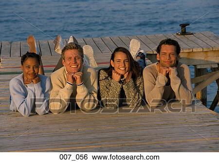 Stock Photograph - Friends lying on pier. Fotosearch