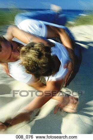 Couple rolling in the sand View Large Photo Image Stock Photograph - Couple rolling in the sand. Fotosearch