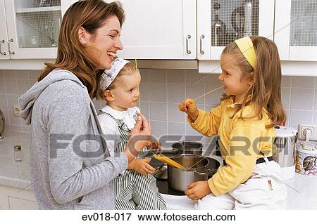 Stock Photo - Mother and daughters in kitchen. Fotosearch
