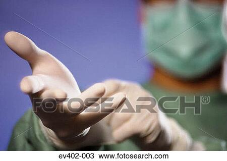 Stock Image - Surgeon putting on gloves. Fotosearch