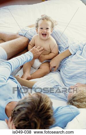 Mother and father with baby in bed View Large Photo Image Stock Photo - Mother and father with baby in bed . Fotosearch