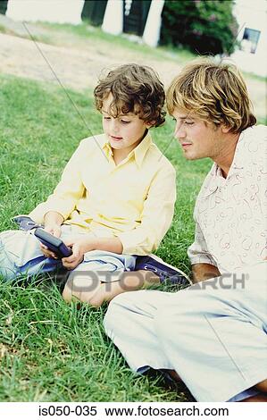 Stock Photography - Father and son playing handheld game. Fotosearch