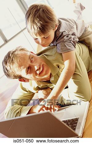 Father and son playing with a laptop View Large Photo Image Stock Image - Father and son playing with a laptop. Fotosearch