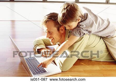 Stock Photo - Father and son playing with a laptop. Fotosearch