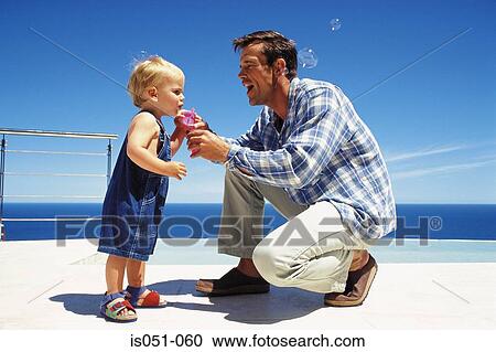 Father blowing soap bubbles with toddler View Large Photo Image Stock Image - Father blowing soap bubbles with toddler . Fotosearch