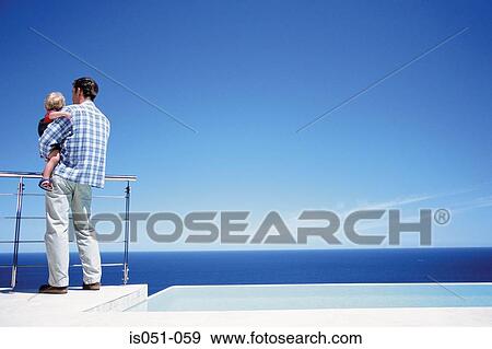 Father holding toddler enjoying a view of the sea View Large Photo Image Stock Photo - Father holding toddler enjoying a view of the sea. Fotosearch