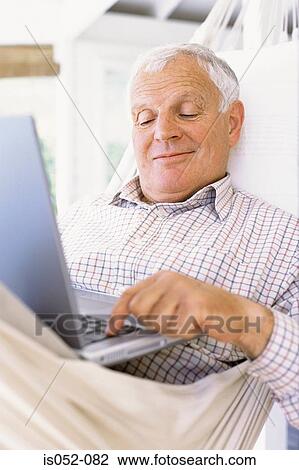 Stock Image - Granddad with a laptop in a hammock. Fotosearch