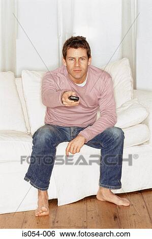 Stock Photograph - Grumpy young man watching TV. Fotosearch