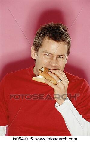 Young man eating a sandwich View Large Photo Image Stock Photography - Young man eating a sandwich. Fotosearch