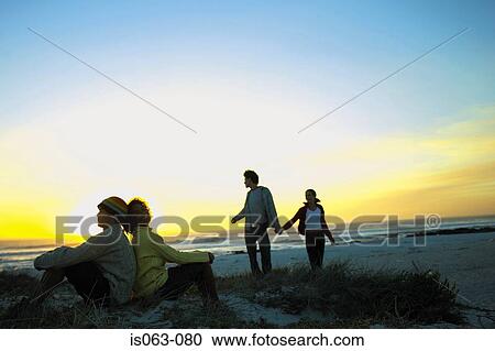 Stock Image - Couples watching sunset. Fotosearch