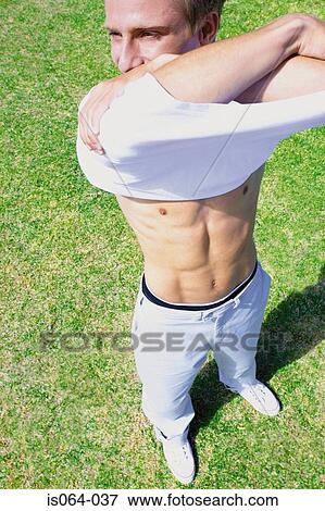 Man taking off shirt View Large Photo Image Stock Photo - Man taking off shirt. Fotosearch