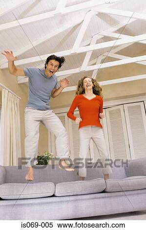 Couple jumping on sofa View Large Photo Image Stock Photography - Couple jumping on sofa. Fotosearch