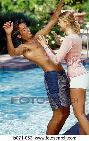 Woman pushing man into pool View Large Photo Image Stock Image - Woman pushing man into pool. Fotosearch
