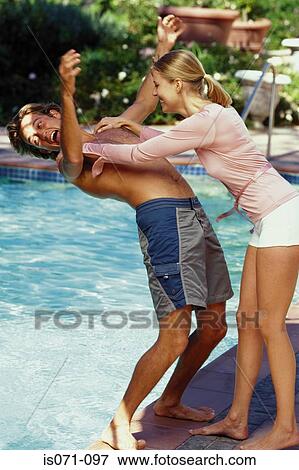 Stock Photo - Woman pushing man into pool. Fotosearch