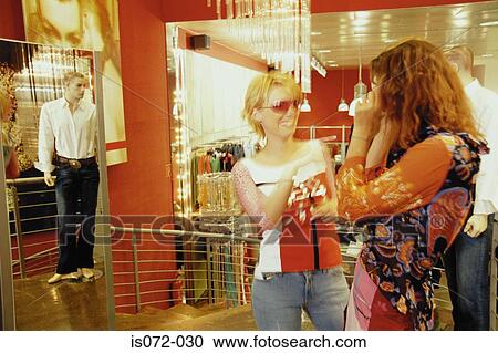 Stock Image - Girls in clothes shop. Fotosearch