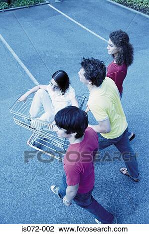 Stock Image - Teenagers with shopping trolley. Fotosearch