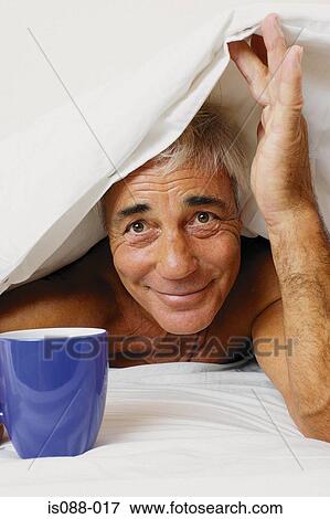 Stock Photo - Man under duvet. Fotosearch