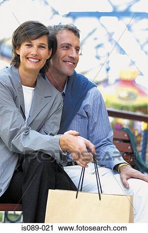 Stock Image - Man and woman sitting on street bench. Fotosearch