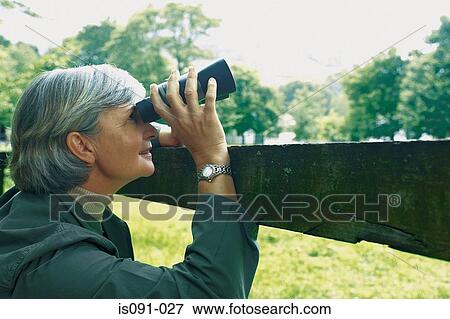 Woman looking through binoculars View Large Photo Image Stock Photo - Woman looking through binoculars. Fotosearch