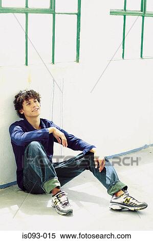 Stock Photography - Man sitting against wall. Fotosearch