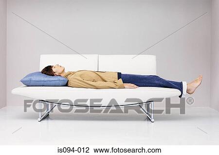 Man lying down on modern sofa View Large Photo Image Stock Image - Man lying down on modern sofa. Fotosearch