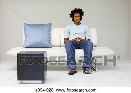 Stock Photo - Man sitting on modern sofa. Fotosearch