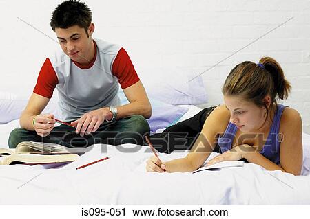Stock Image - Teenage boy and girl doing homework. Fotosearch