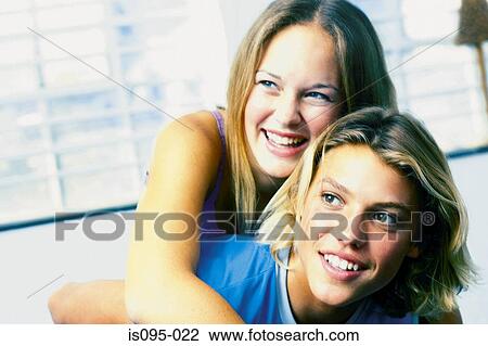 Stock Image - Teenage boy giving piggyback to teenage girl. Fotosearch