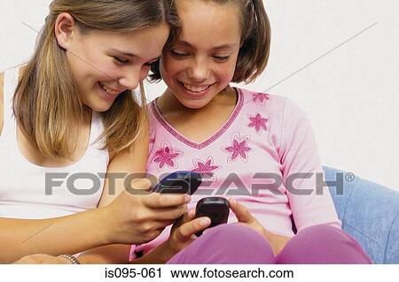 Stock Image - Teenage girls with mobile telephones. Fotosearch