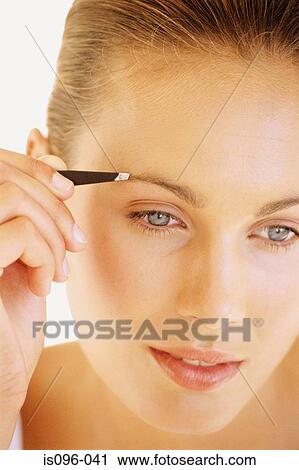 Stock Image - Woman plucking eyebrow. Fotosearch