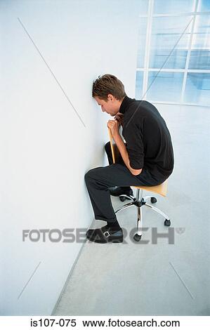 Stock Photography - Businessman seated against a wall. Fotosearch