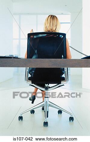 Stock Image - Businesswoman working on modern office furniture. Fotosearch