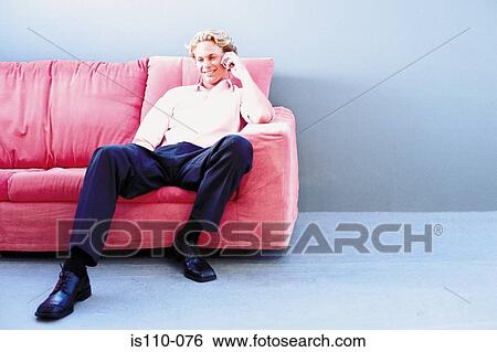 Man sitting on sofa View Large Photo Image Stock Photograph - Man sitting on sofa. Fotosearch