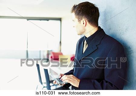 Man typing on personal organiser View Large Photo Image Stock Image - Man typing on personal organiser. Fotosearch
